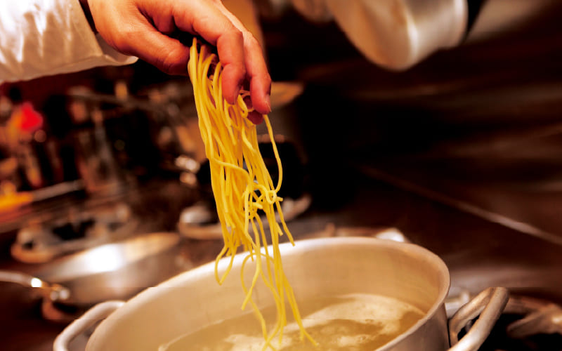 自家製生パスタを鍋から持ち上げる様子